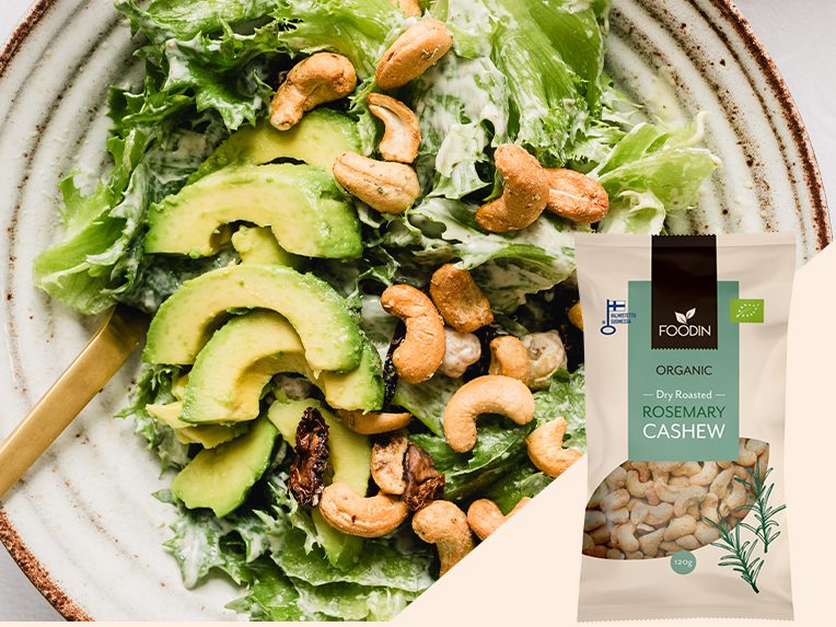Salade verte avec avocat, noix de cajou et un sachet de graines à côté.bio